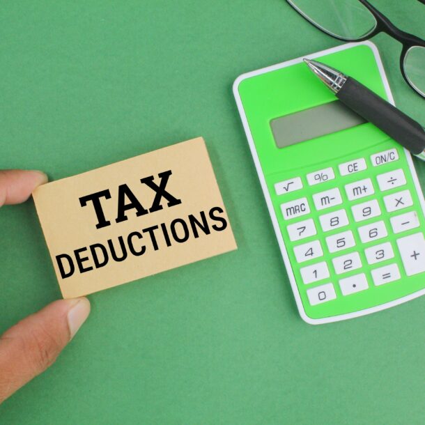 pen, calculator, glasses and paper with the word Tax Deductions.