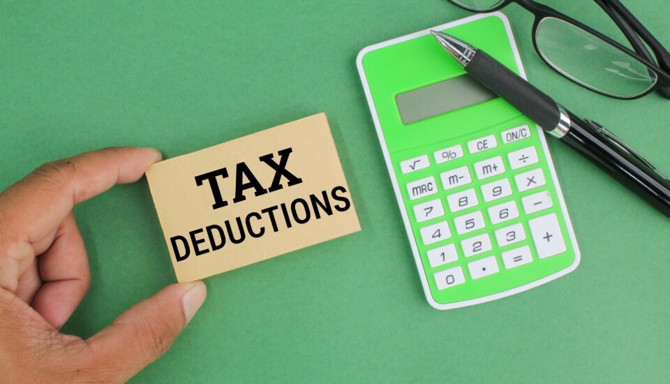 pen, calculator, glasses and paper with the word Tax Deductions.